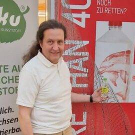 Johann Zimmermann mit einer Flasche des NOT PLASTIC WATERS von Wildlap bei der Kunstausstellung "More than 40.000" in Hamburg.