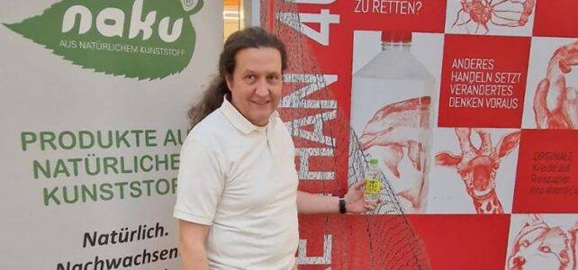 Johann Zimmermann mit einer Flasche des NOT PLASTIC WATERS von Wildlap bei der Kunstausstellung "More than 40.000" in Hamburg.